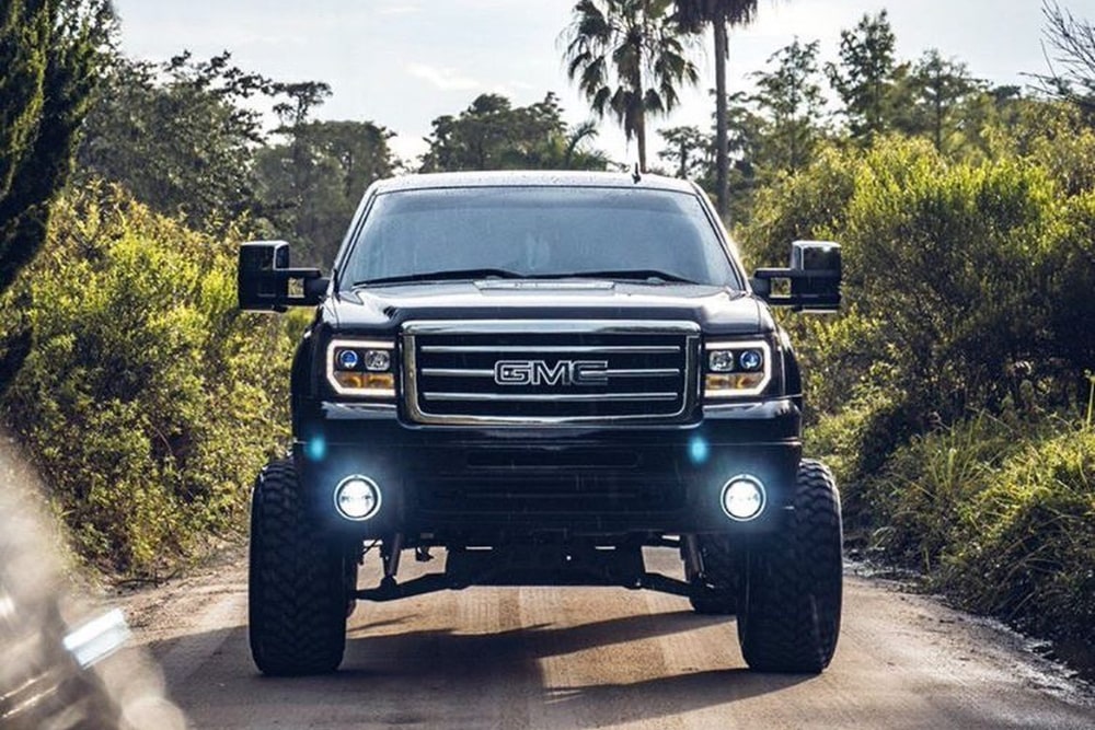 Front view of a dark colored GMC pickup trick with bright LED headlights.