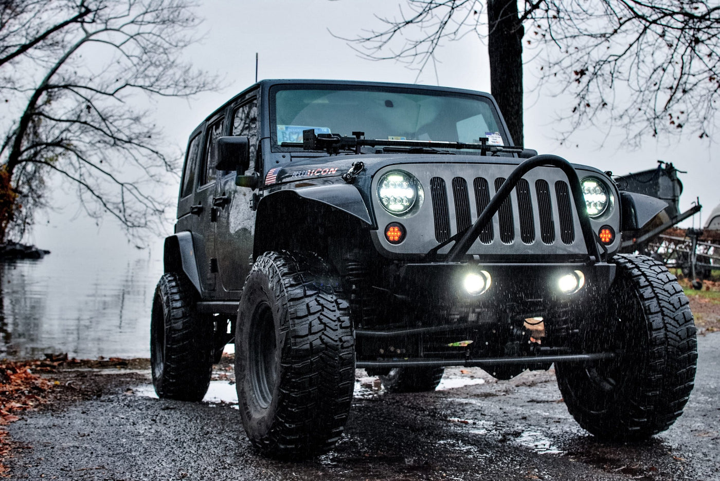 Black Jeep at the head of a rainy off-road trail.